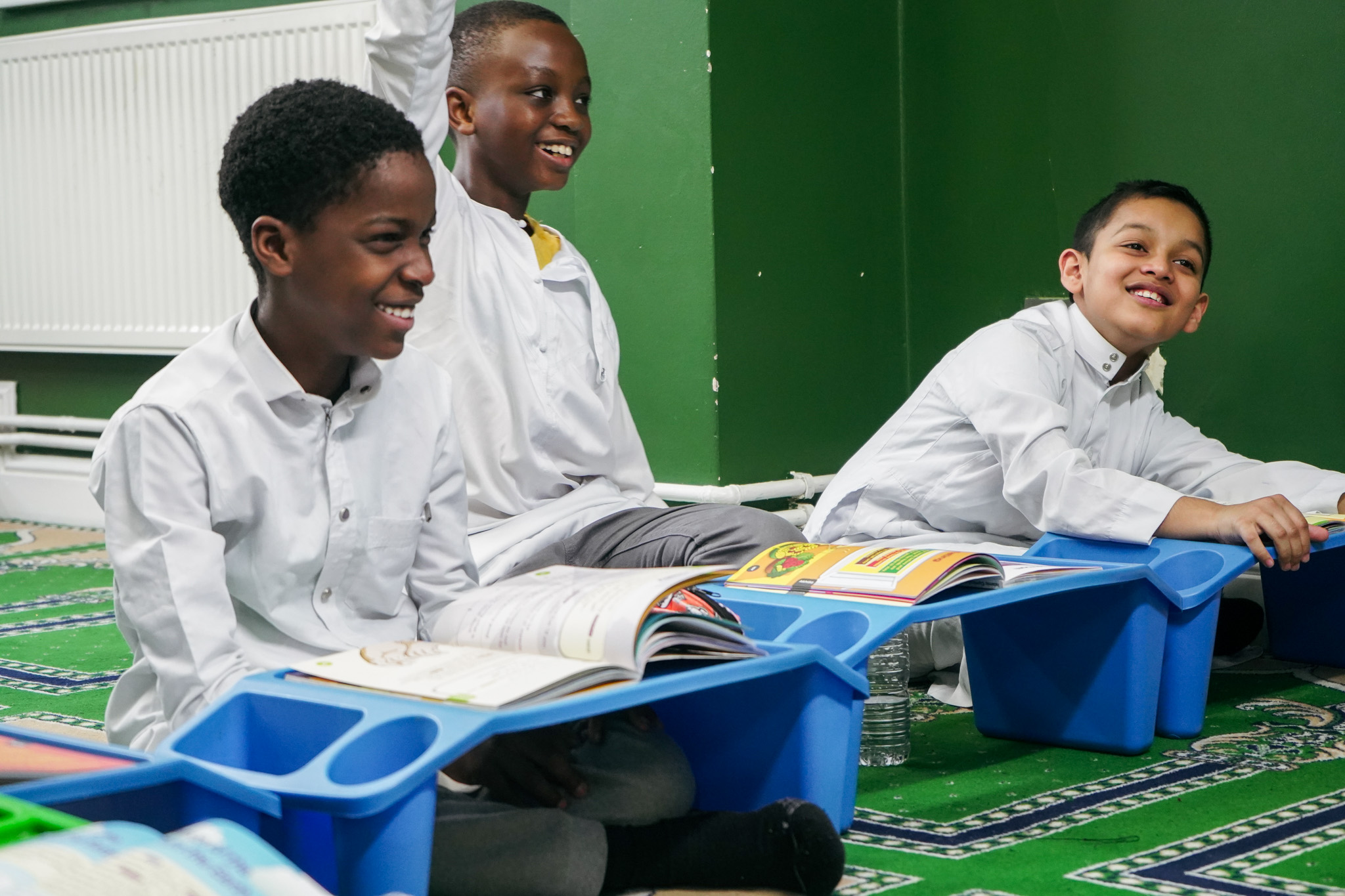 An open Qur'an on a wooden stand in a bright classroom